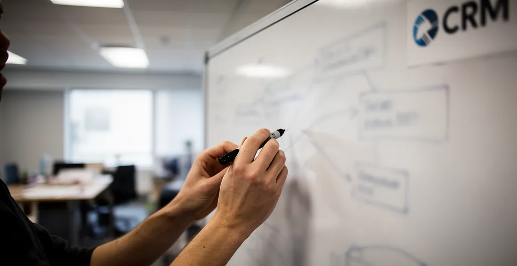 Close-up of hands mapping CRM fields to billing system on whiteboard